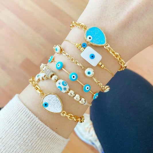 Gold Evil Eye Bracelets featuring blue charms on a wrist, showcasing adjustable stainless steel cuff design with protective symbolism.